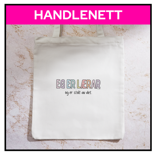 Handlenett "Eg er lærar og eg er stolt av det". Liggende på et bord. 